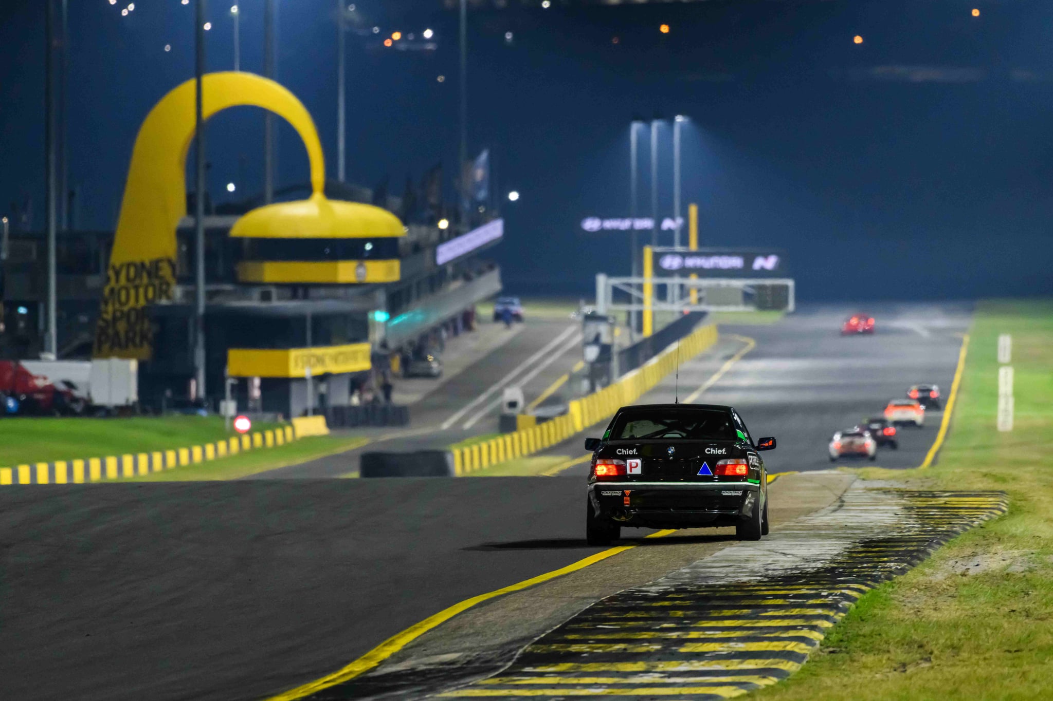 Project E36 #17 heading toward the iconic Sydney Motorsport Park arch under lights at the 2026 Sydney 300