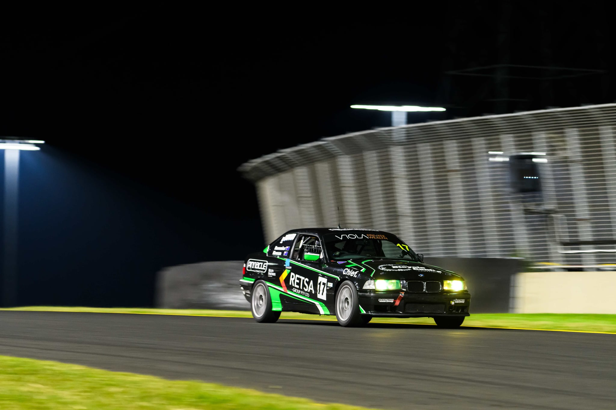 Project E36 #17 sweeping past the floodlit grandstand under lights at the 2026 Sydney 300